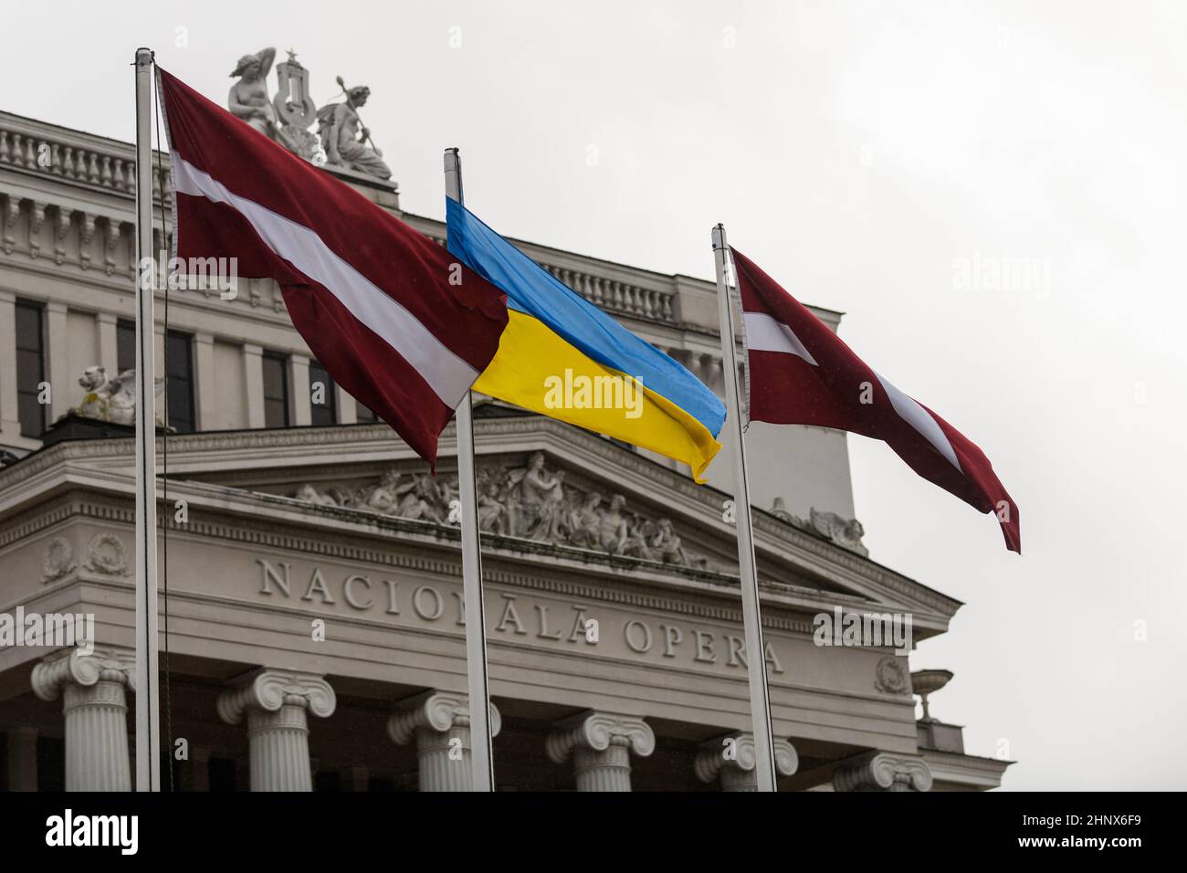 RIGA, LATVIA. 17th February 2022. Selective focus photo. Latvian and Ukrainian flags waves in front of National Opera of Latvia building. Stock Photo