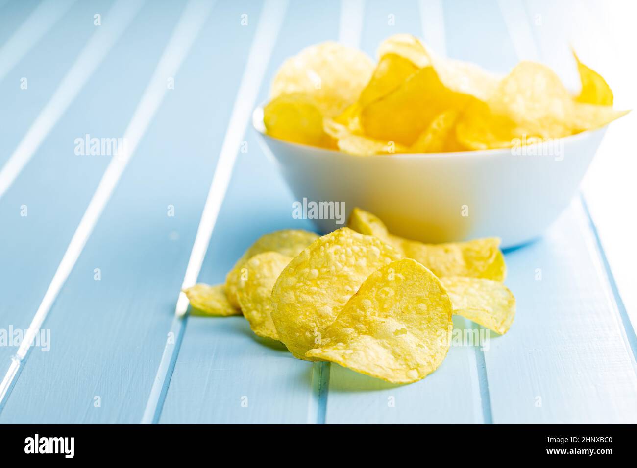 Crunchy potato chips. Potato crisps on blue table Stock Photo Alamy