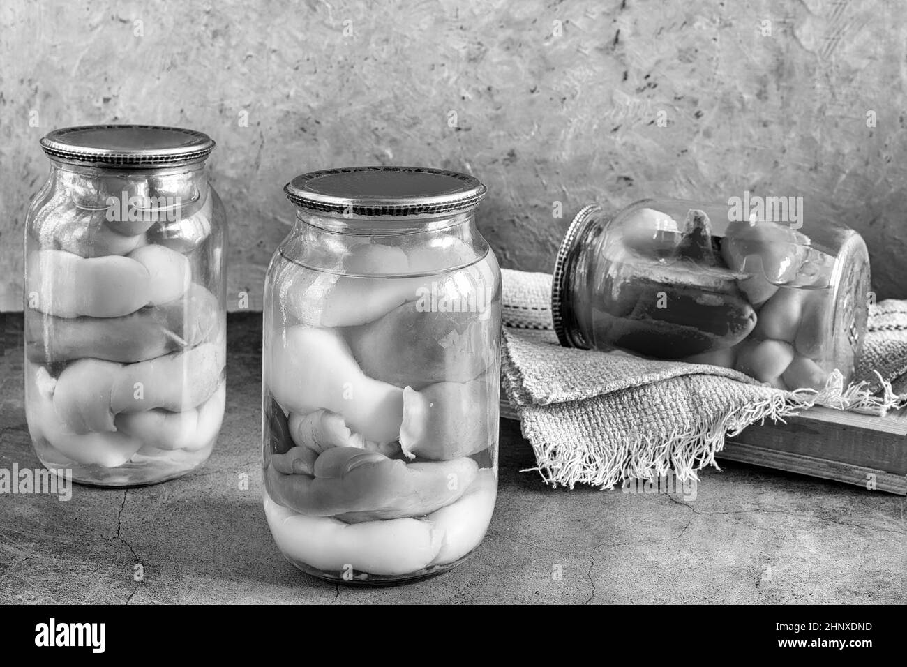 Canned bell peppers in glass jars, intended for further stuffing. Home canning. Front view, copy space. Black and white photo. Stock Photo