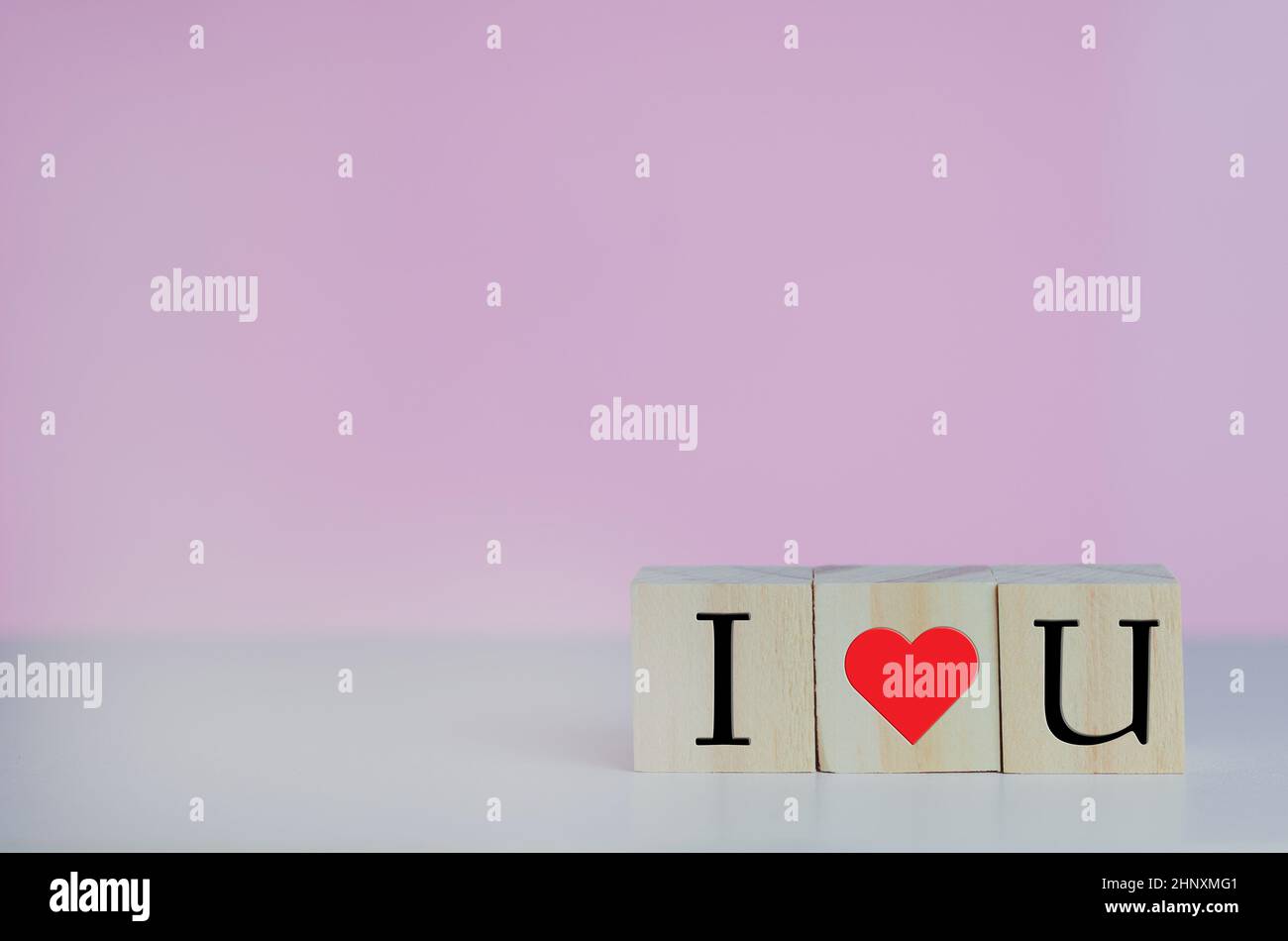 Wooden cubes with i love u symbol heart on the pink background and copy ...