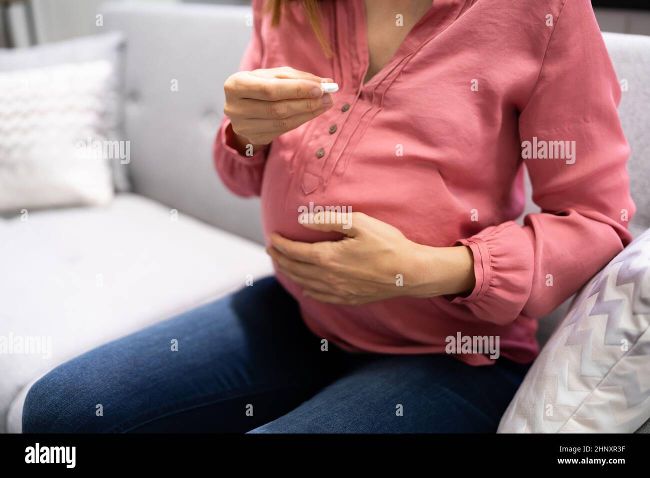 Pregnant Woman Taking Vitamin Pill. Folic Acid In Pregnancy Stock Photo