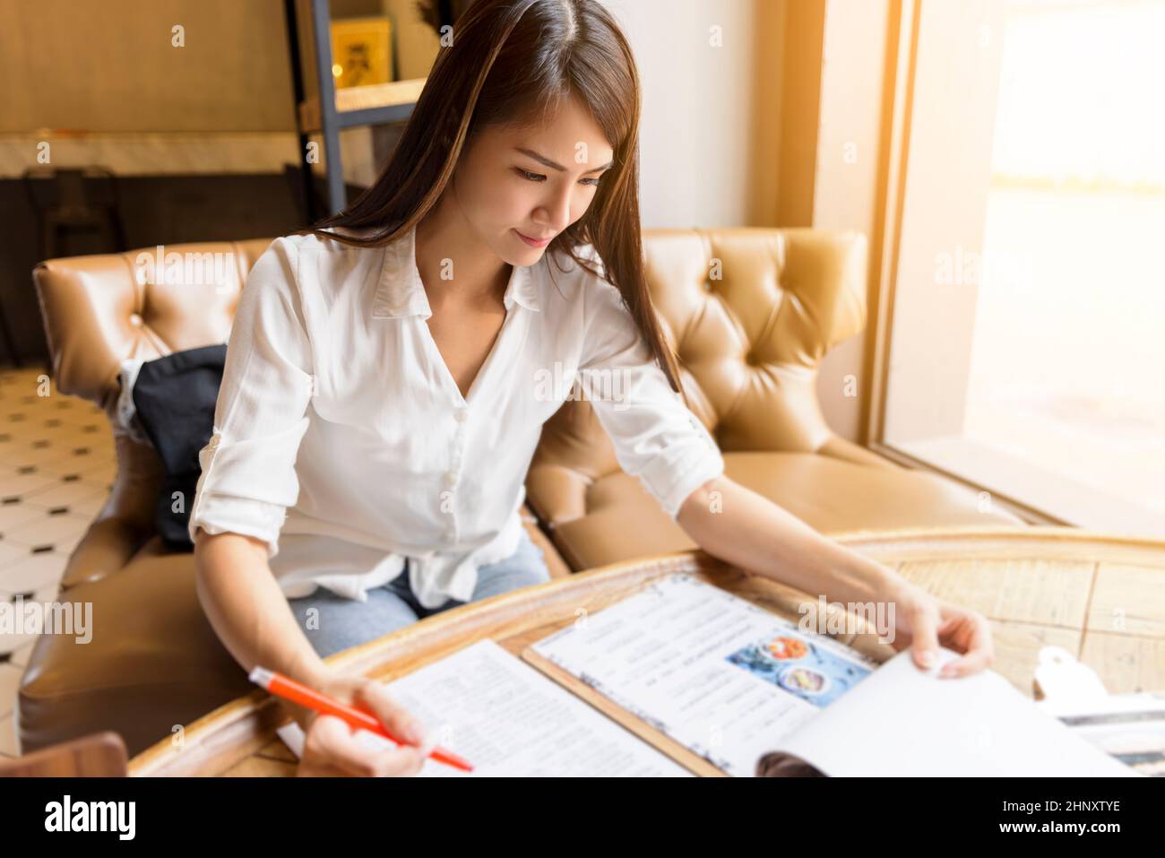 Young woman reading menu in restaurant. Stock Photo