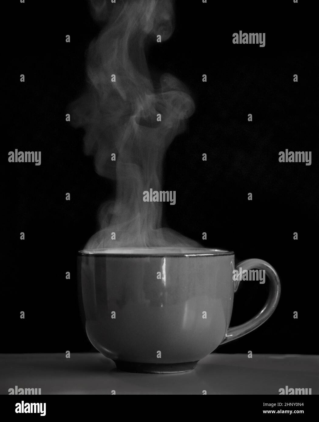 Black and white closeup of a coffee cup with steam coming out of it Stock Photo