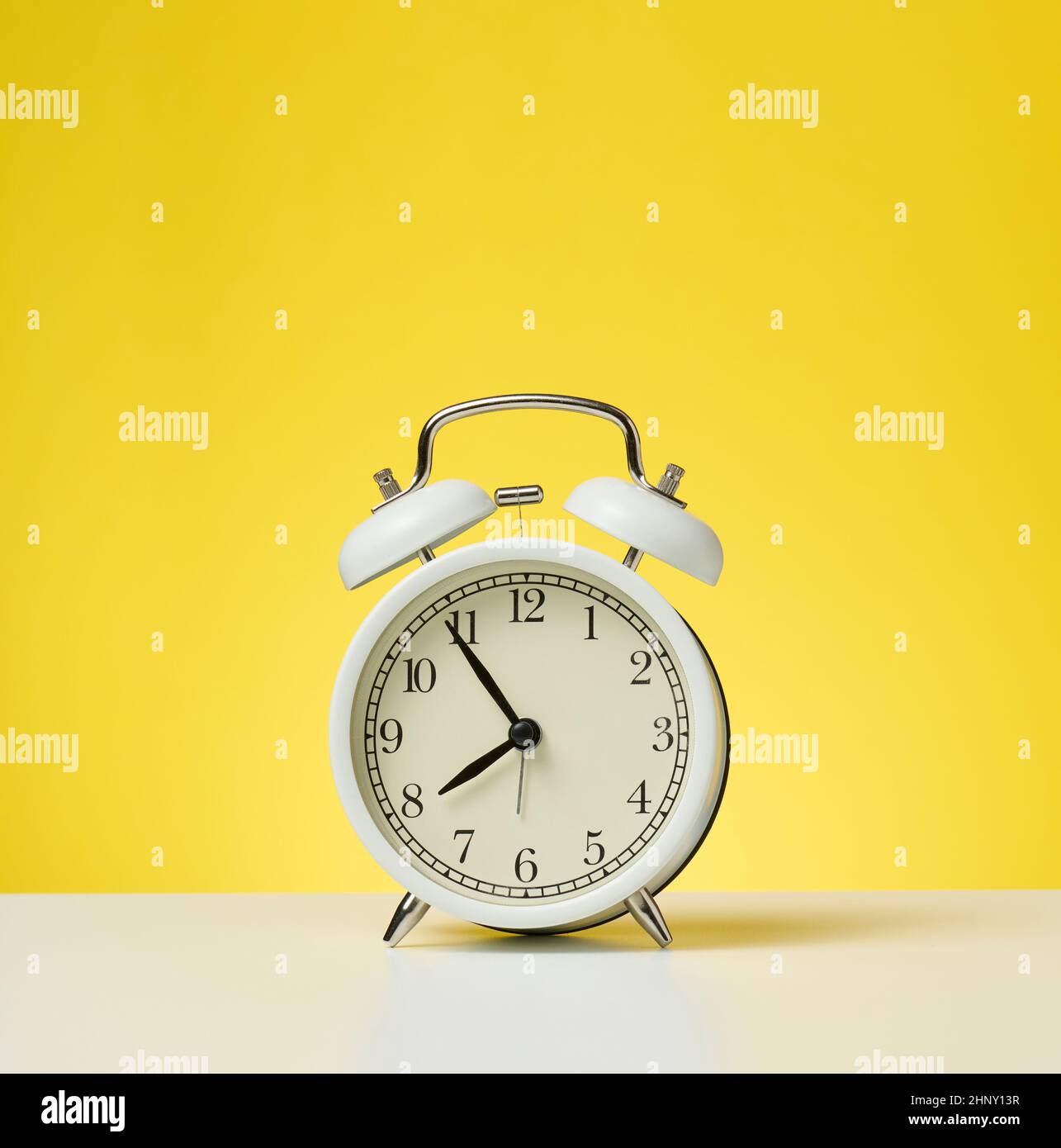 round white alarm clock, five minutes to eight in the morning. Yellow