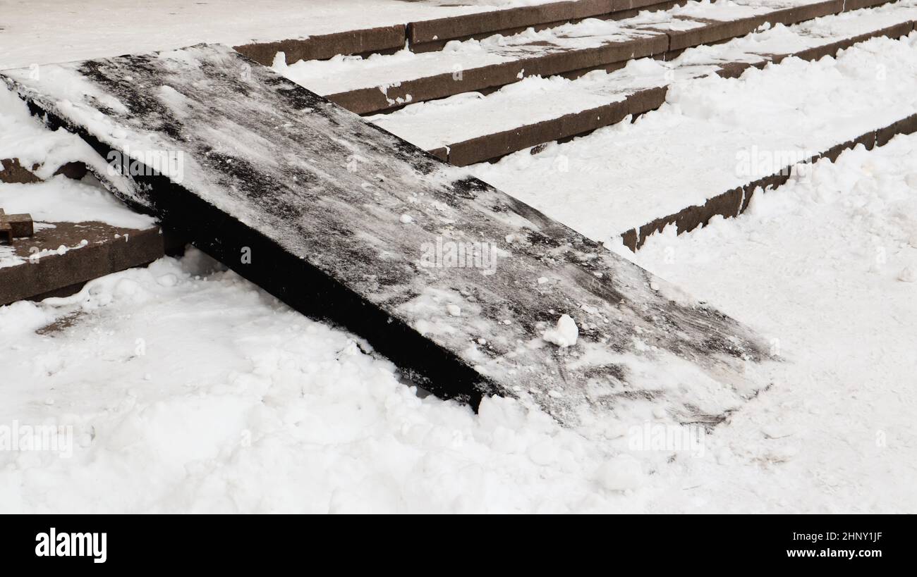 Snow covered slippery concrete stairs and wooden ramp. First snow on