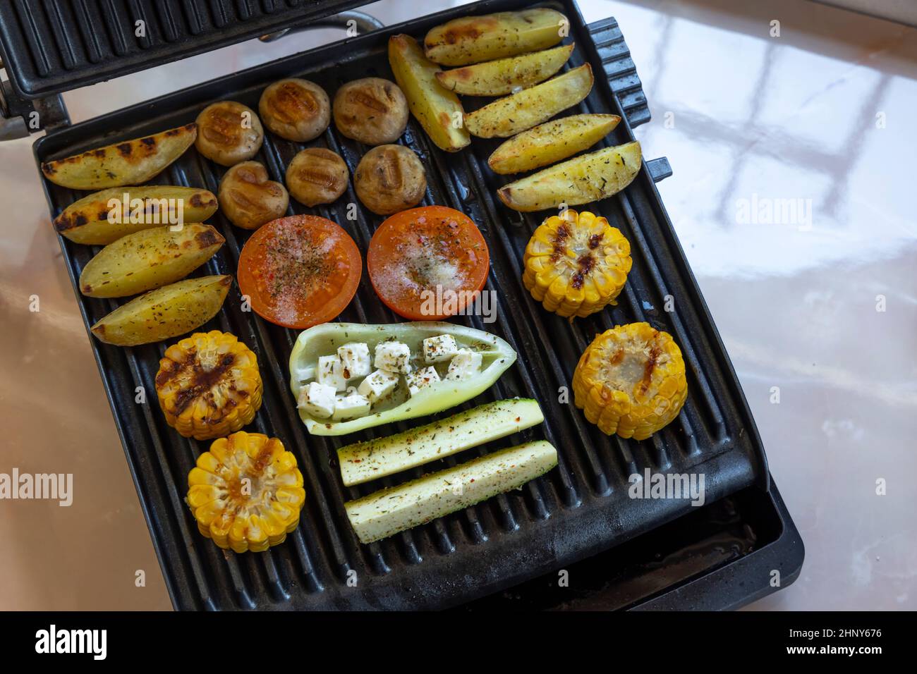 Electric grill with spicy potatoes, mushrooms and vegetables Stock