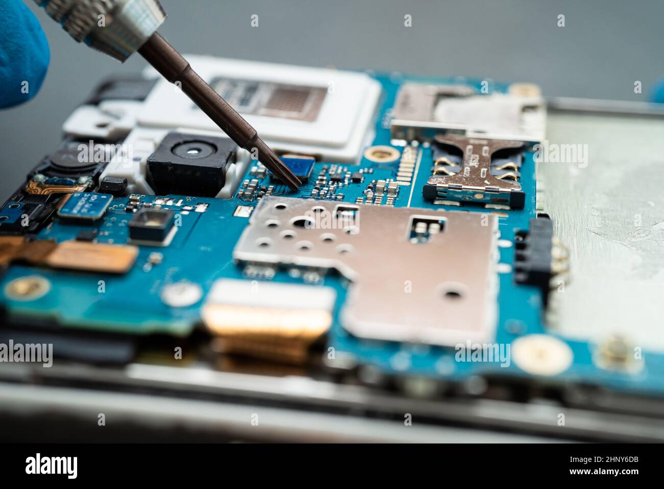 Technician repairing inside of mobile phone by soldering iron