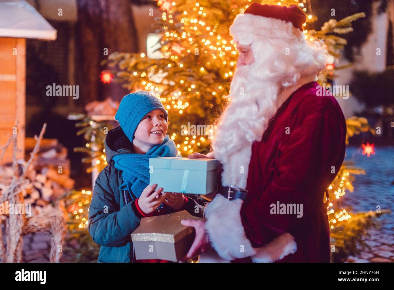 Boy receives a present from Santa Claus himself in front of Christmas tree Stock Photo