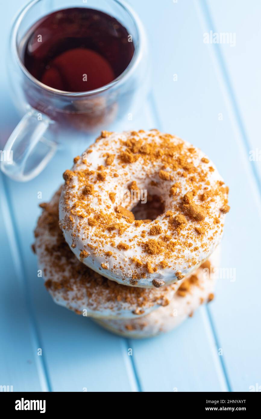 Sweet glazed donut with sprinkles and tea on blue kitchen table Stock