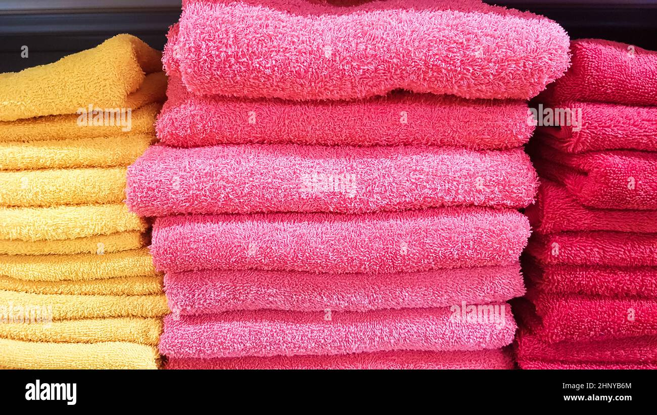 Stacks of fluffy bath towels of various colors in a store window. Terry