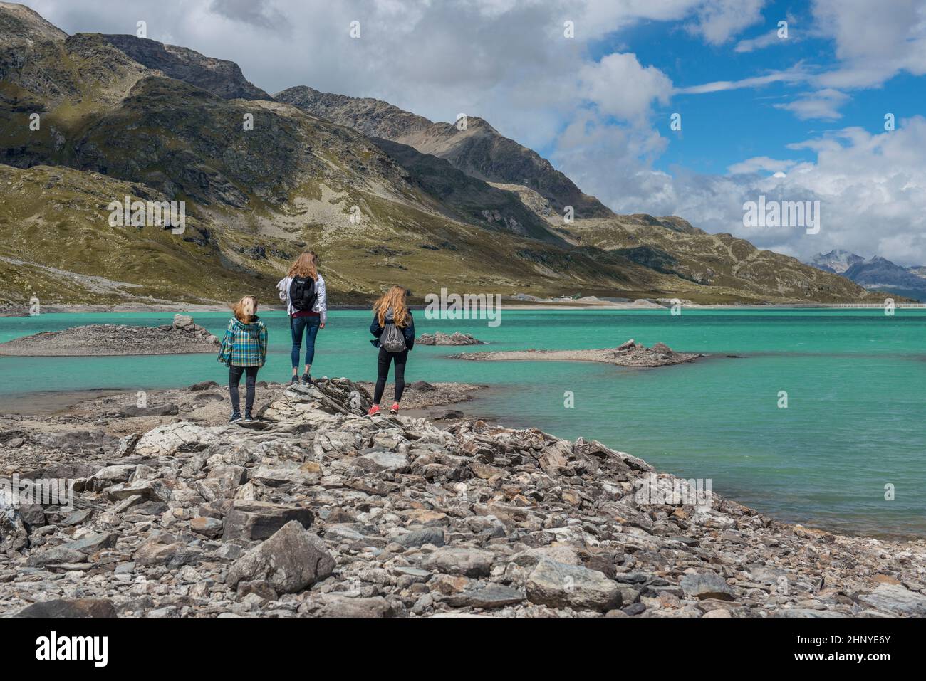 Girls standing high up in the swiss mountains in front of a blue lake Stock Photo
