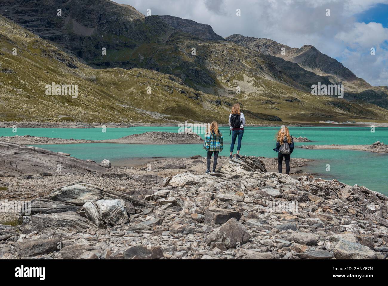 Girls standing high up in the swiss mountains in front of a blue lake Stock Photo