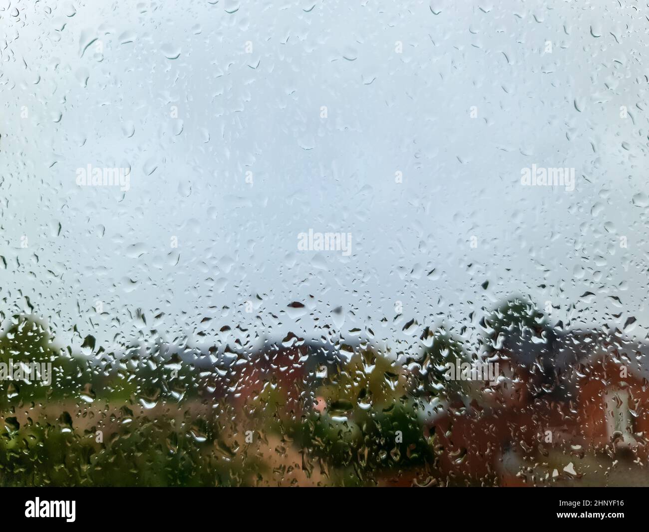 Rain drops running down a car window in a close up view Stock Photo