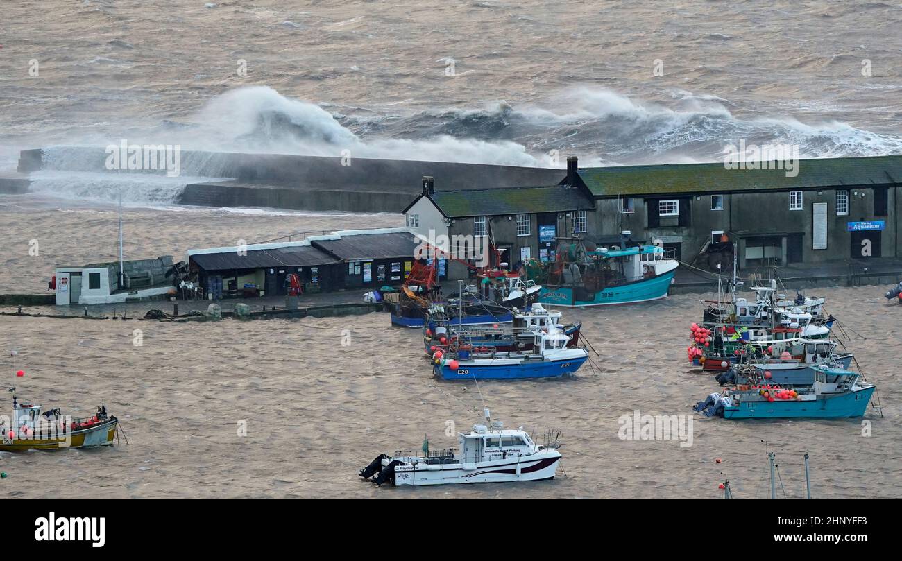 Waves crash over the sea wall at the harbour in Lyme Regis in Dorset as