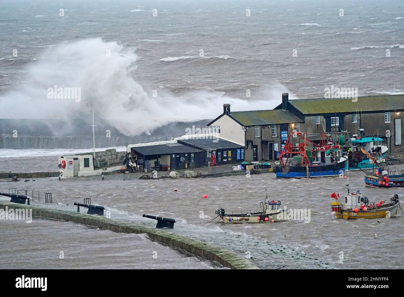 Waves crash over the sea wall at the harbour in Lyme Regis in Dorset as