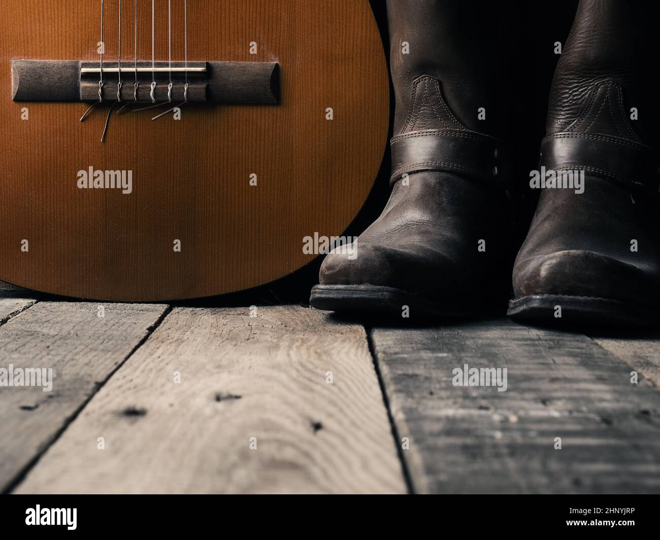 Old cowboy boots with an acoustic guitar on barn wood, space for your text Stock Photo