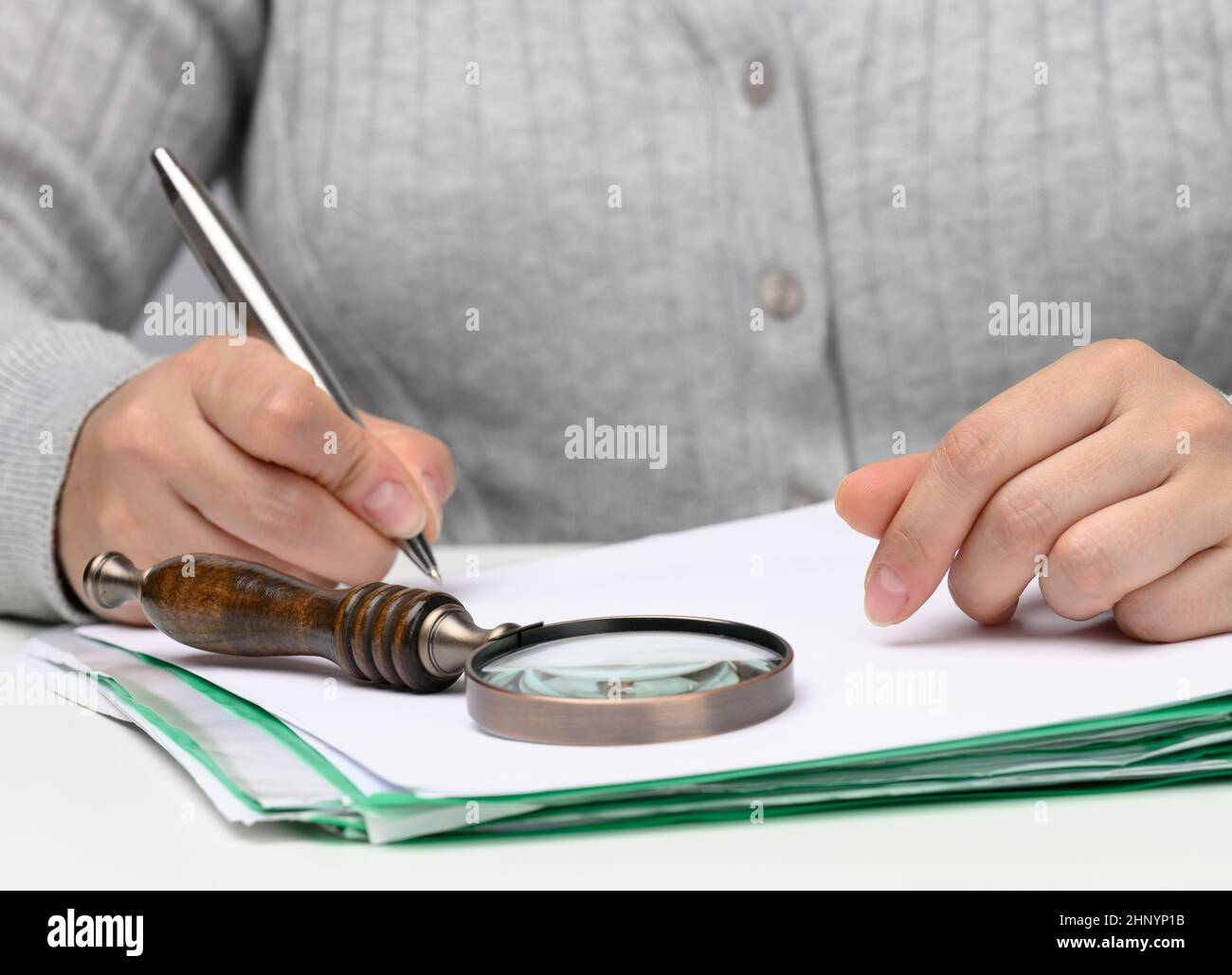 woman of Caucasian appearance sits in gray clothes at a white table and ...
