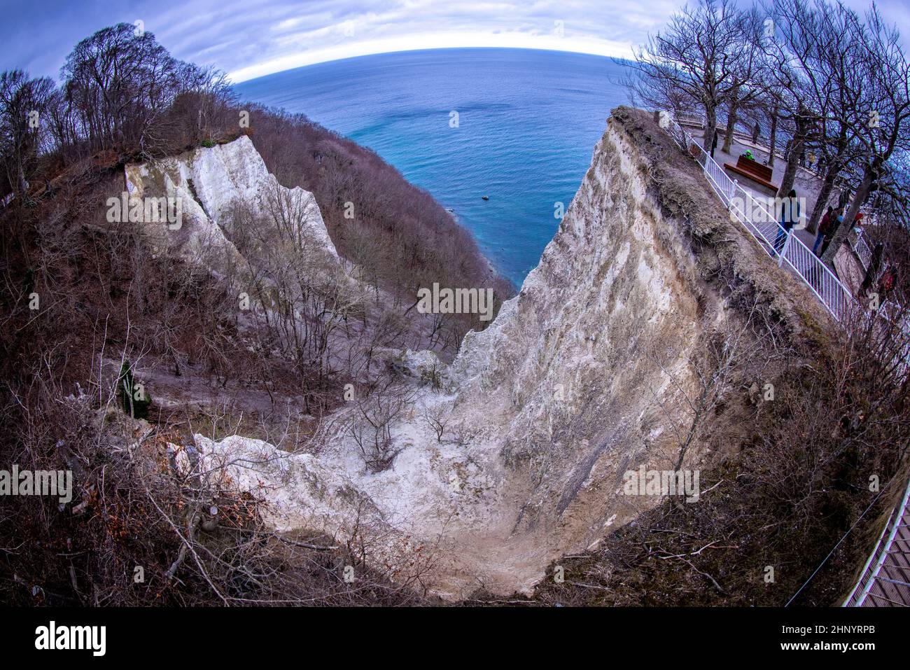 15 February 2022, Mecklenburg-Western Pomerania, Sassnitz: Visitors walk up a staircase to the Königsstuhl viewing platform on the chalk coast of the island of Rügen, which is only open until the end of April 2022. (Exception with extreme wide-angle lens) Behind it, parts of the chalk coast and the beech forest can be seen. To protect the 118 meter high chalk cliff on the Baltic Sea, visitors will in future be able to admire the view from an oval 185 meter long bridge circuit above the cliff. The new steel structure is to have a load capacity of 163 tons and be able to accommodate up to 1,100 Stock Photo