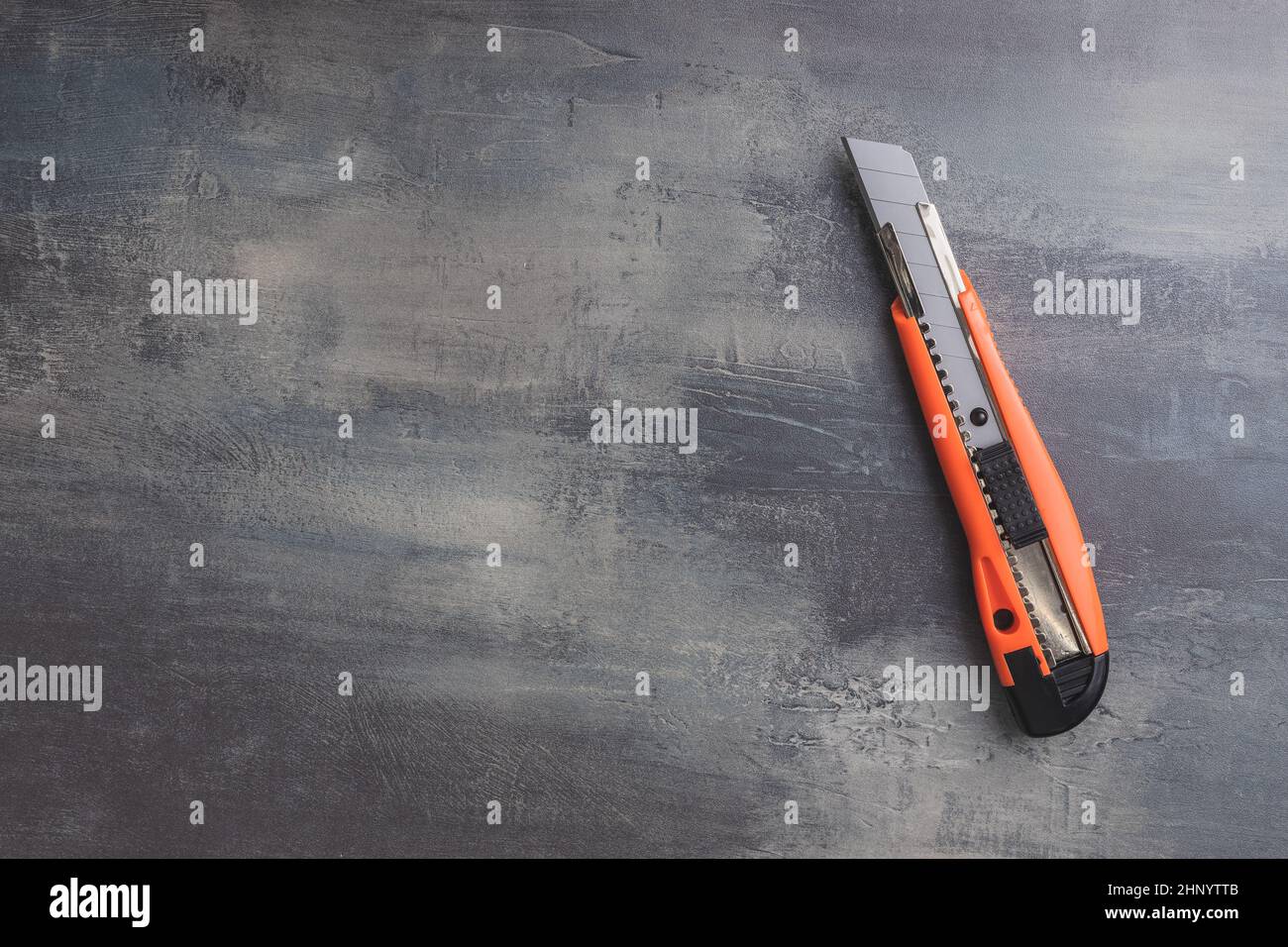 Plastic orange utility knife on table. Top view. Stock Photo