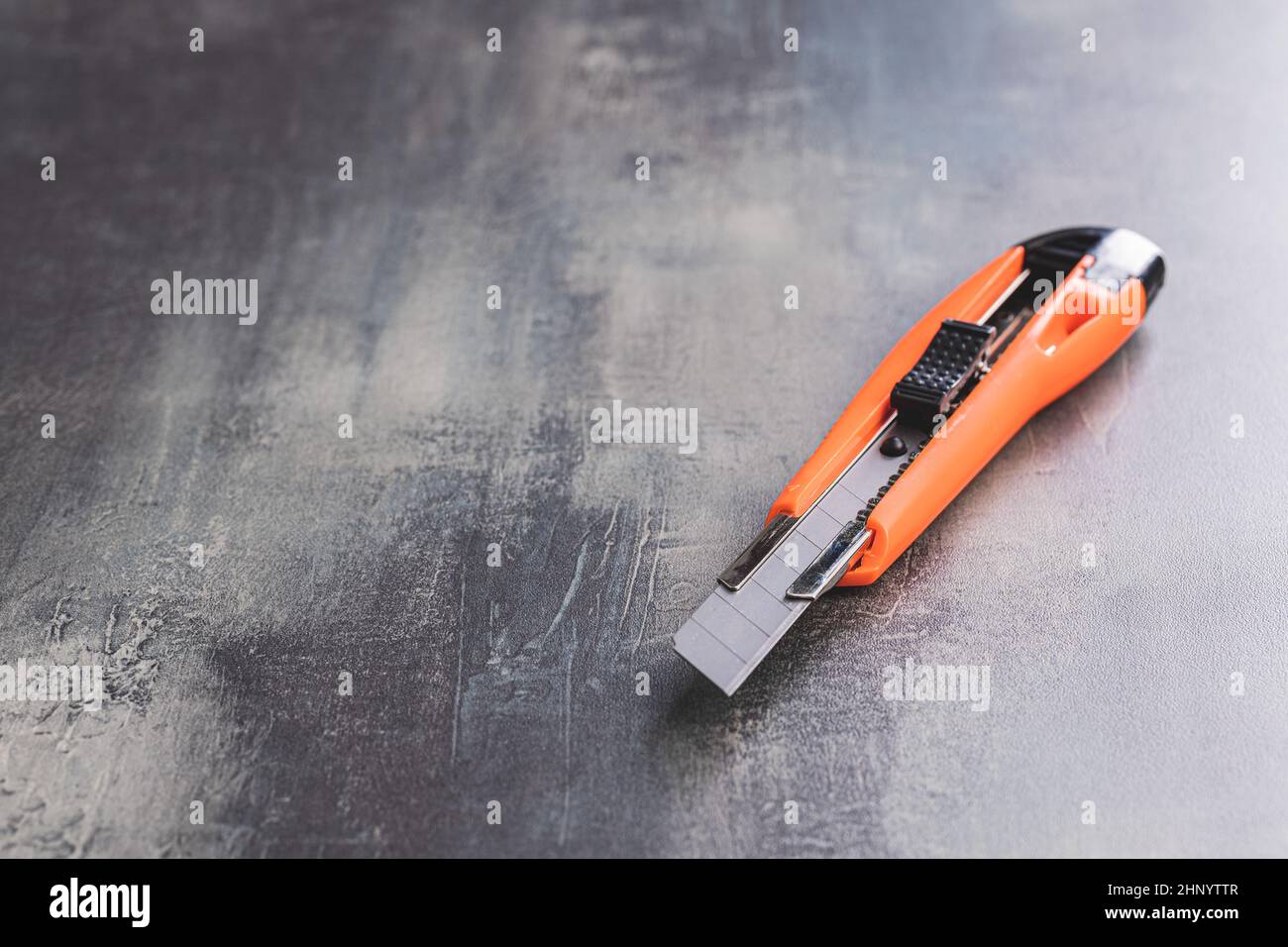 Plastic orange utility knife on table. Stock Photo