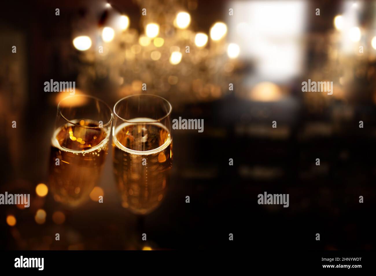 New year celebration with sparkeling champagne. Festive new year's eve background with golden bokeh and space for text. Stock Photo
