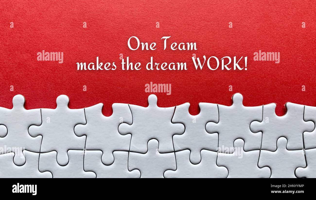 Top view of business quote - One team makes the dream work. With red cover and jigsaw puzzle background. Stock Photo