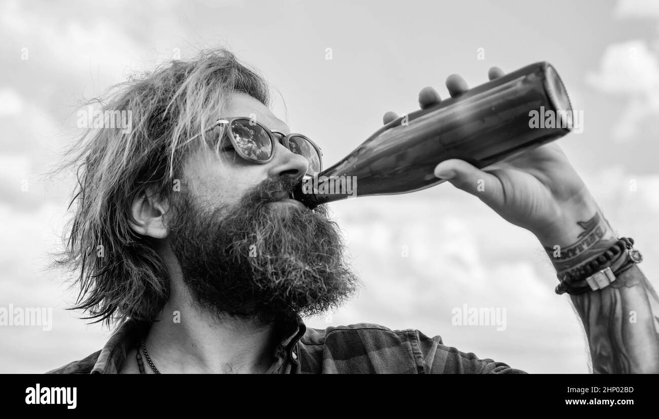 get refreshed and relaxed. mature charismatic male drink beer from bottle. guy with beard and moustache outdoor. drinking beer from glass bottle Stock Photo
