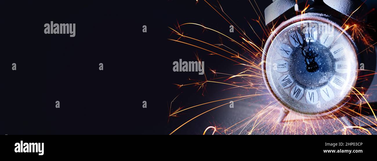 New year countdown with alarm clock and sparkling sparkler on black background. Horizontal close up for new year congratulations with space for your d Stock Photo