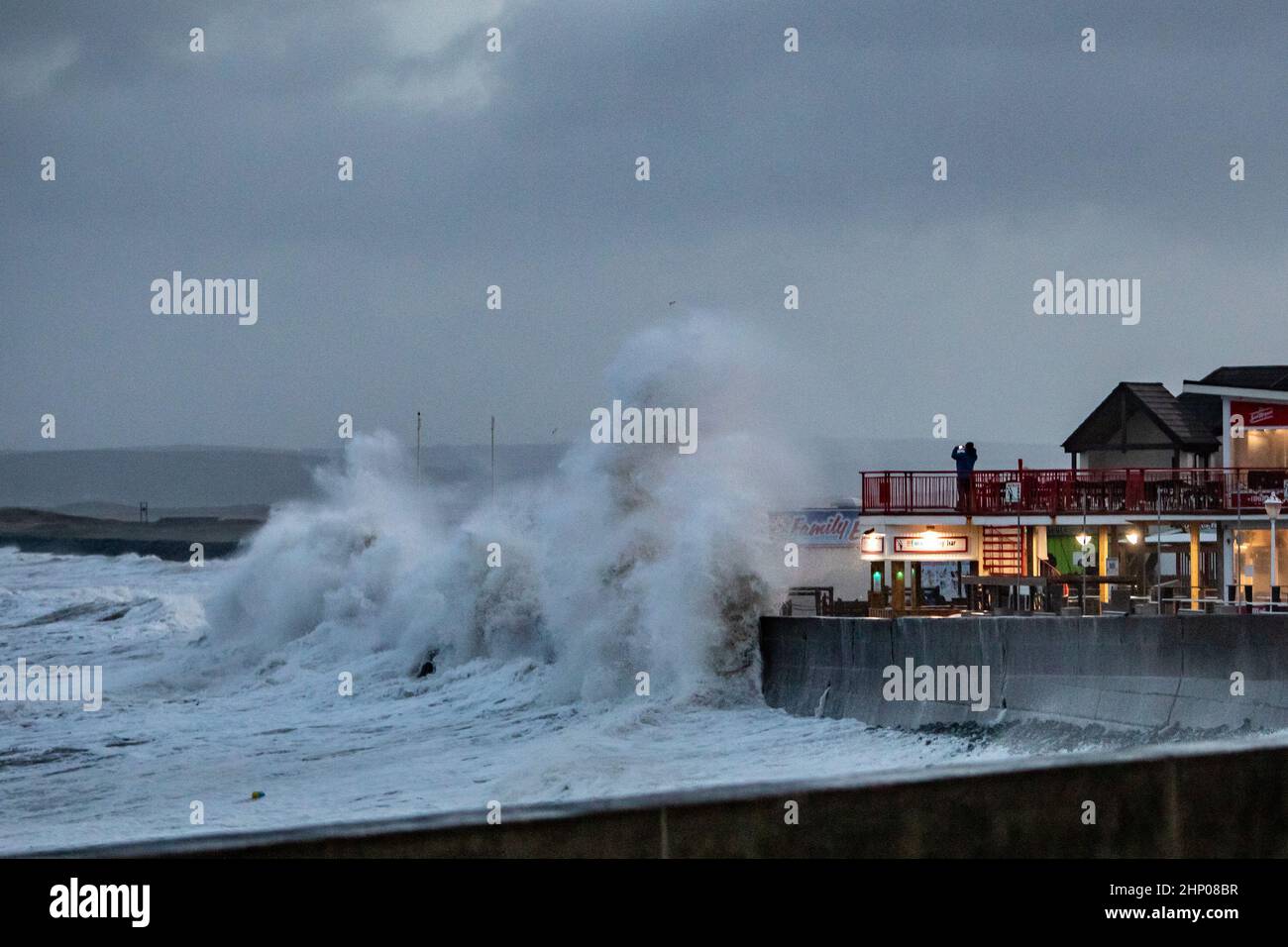 Devon, UK. 18th Feb, 2022. Waves crash onto the seafront at  high tide in Westward Ho! in North Devon as Storm Eunice sweeps across the South West of England Credit: Roy Riley/Alamy Live News Stock Photo