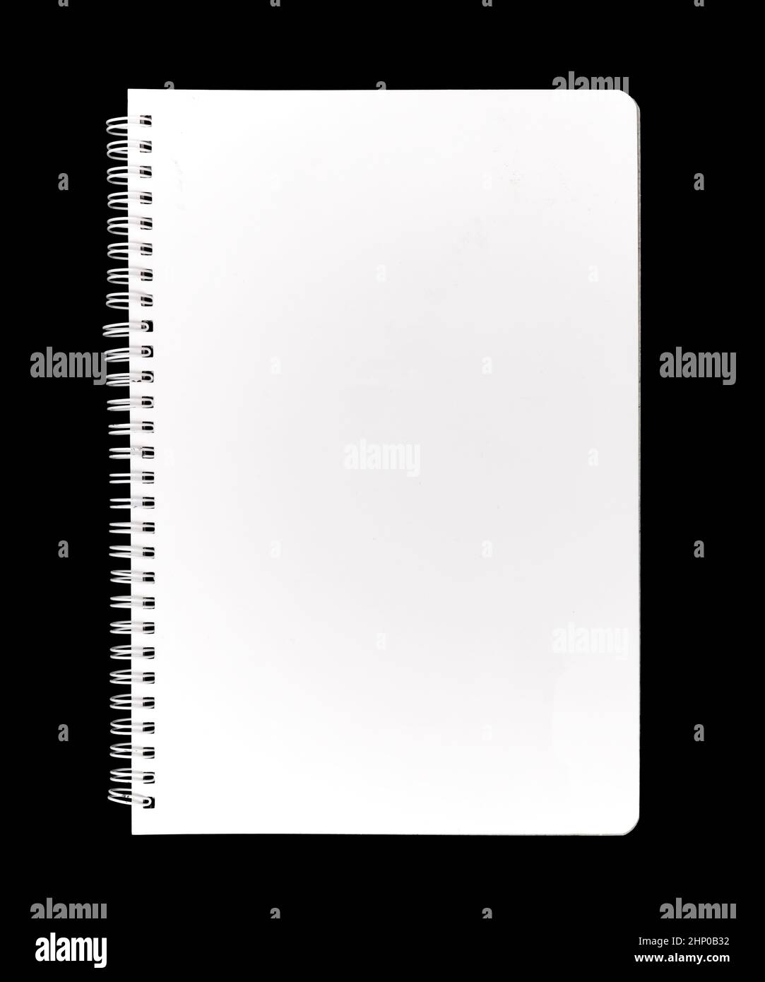 A closed notebook, with a blank empty white cover, isolated on a black background. Stock Photo