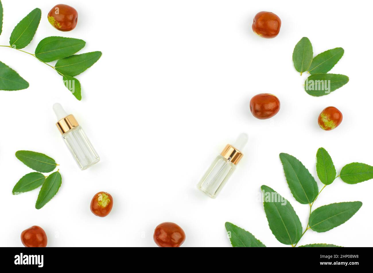 Chinese date fruit and butter, copy space. Jojoba oil in a transparent bottle with a dropper and fresh jojoba fruit on a white background. Stock Photo