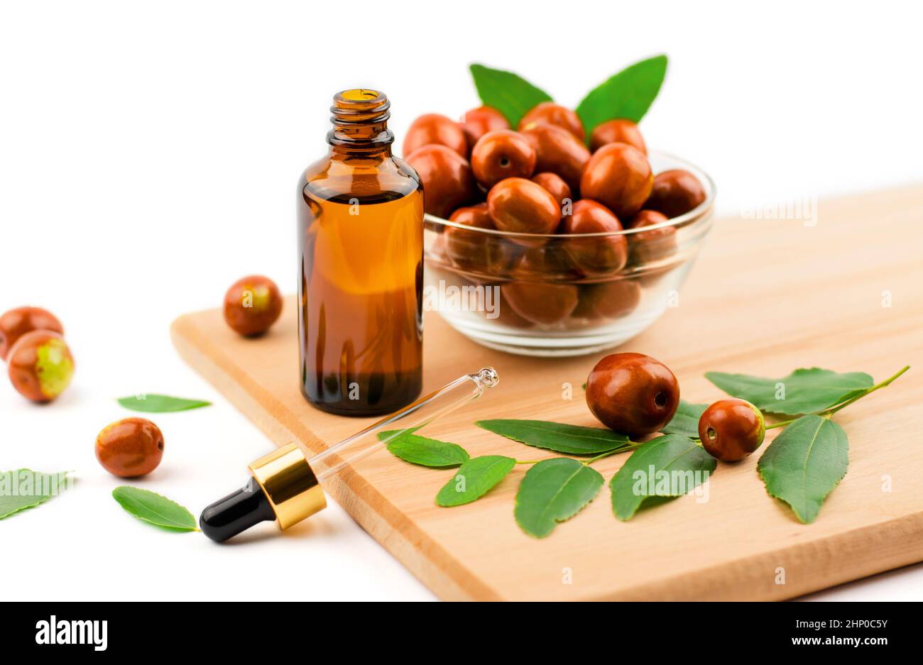 Jojoba oil in a bottle with a dropper on a wooden table with ripe jojoba fruits. Chinese date oil and fruit Stock Photo