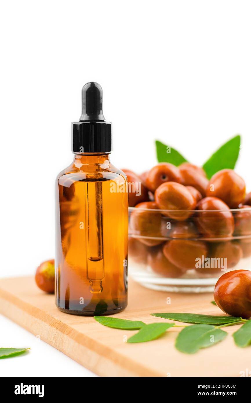 Jojoba oil bottle. Jojoba oil and fresh jojoba fruit on wooden table Stock Photo