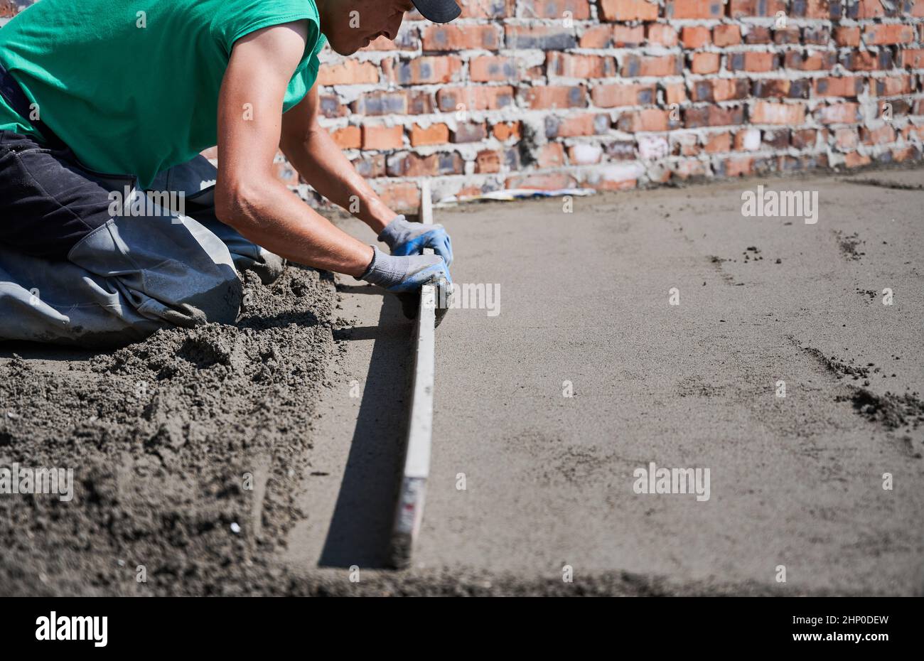 Close up of man builder placing screed rail on the floor covered with