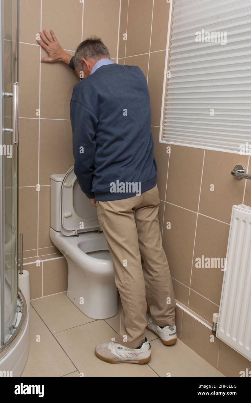 older man with possible prostate problem urinating into toilet, loo