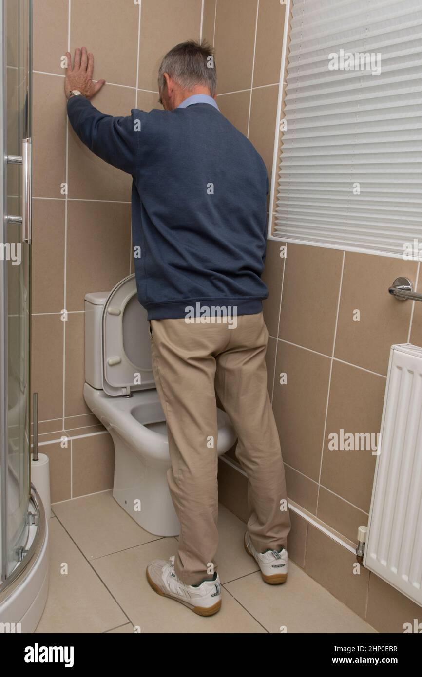 older man with possible prostate problem urinating into toilet, loo