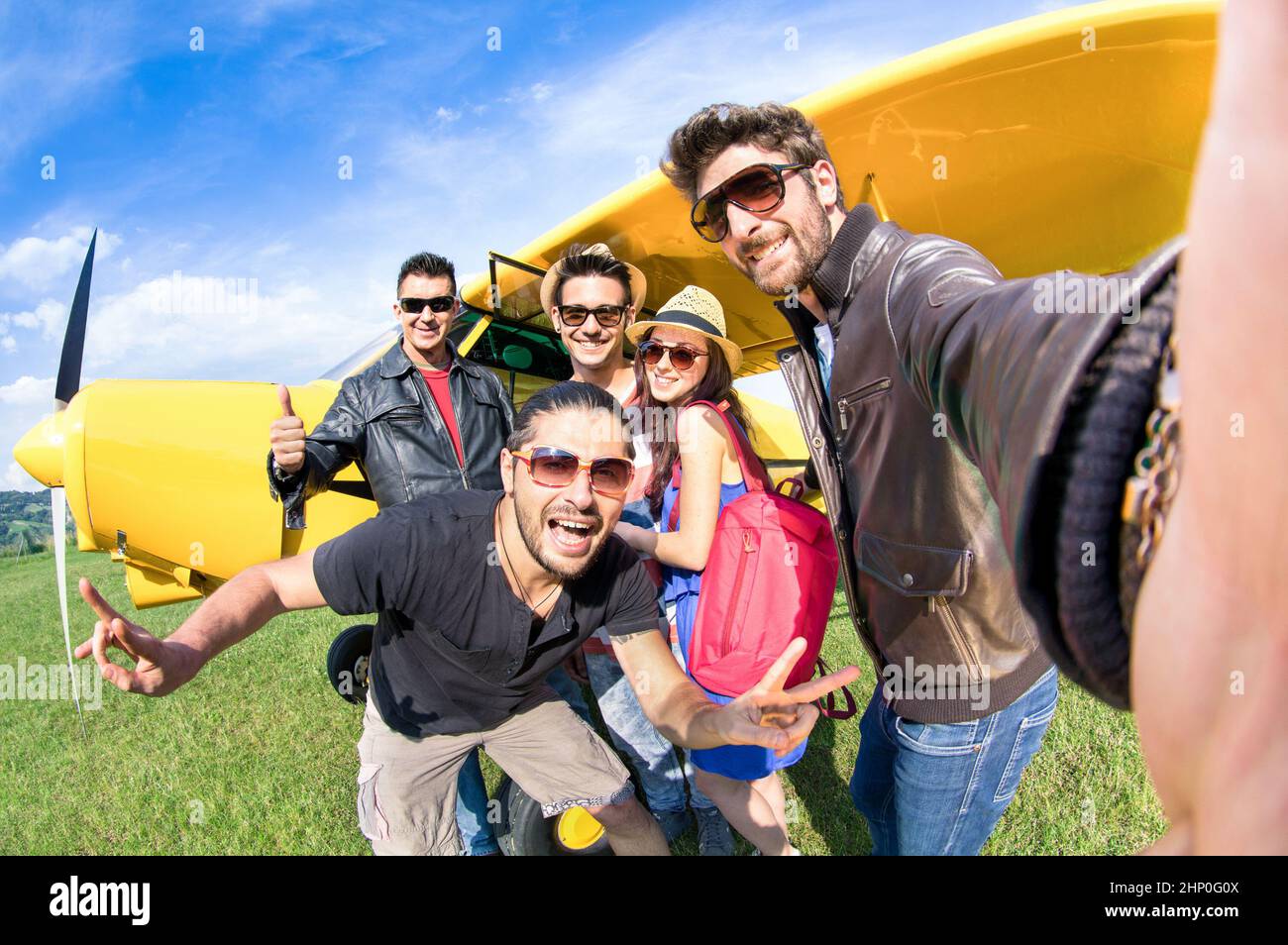 Best friends taking selfie at aeroclub with ultra light airplane - Happy friendship fun concept with young people and new technology trend - Sunny aft Stock Photo