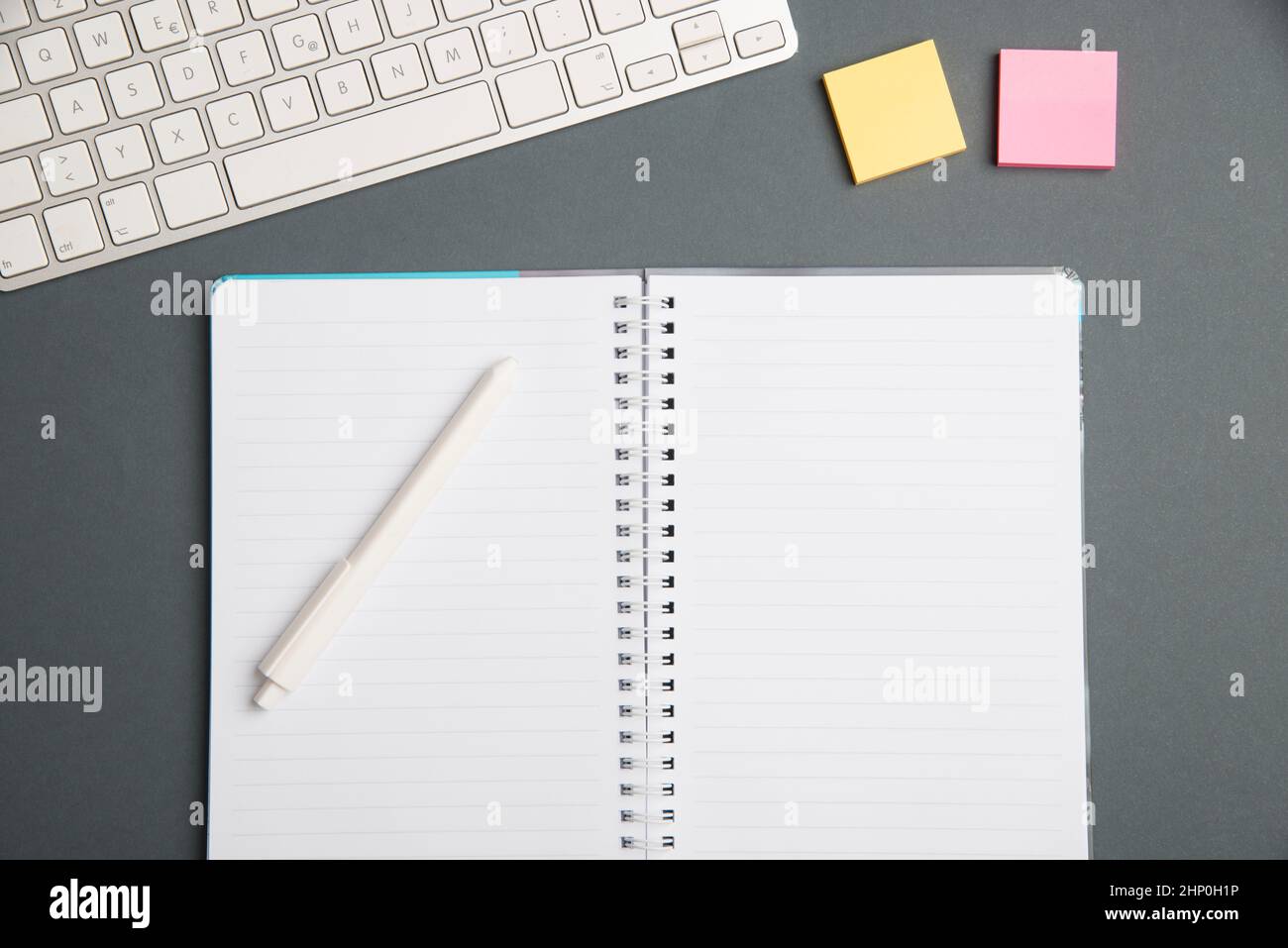 Keyboard Over A Table Beside A Notebook And Pens With Sticky Notes Stock Photo