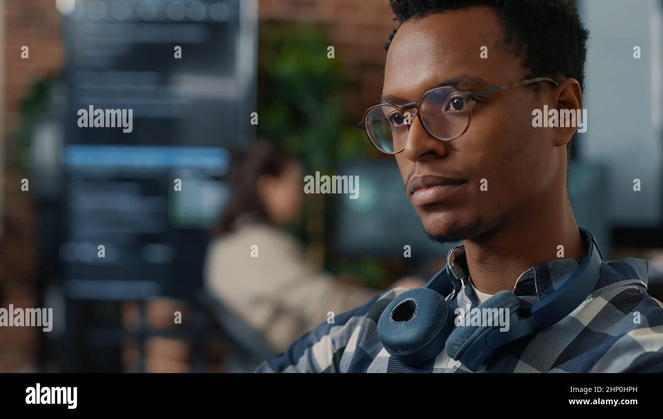 Closeup portrait of software engineer writing code fixing glasses and smiling sitting at desk. Database admin developing algorithms for artificial intelligence to innovate online cloud computing. Stock Photo