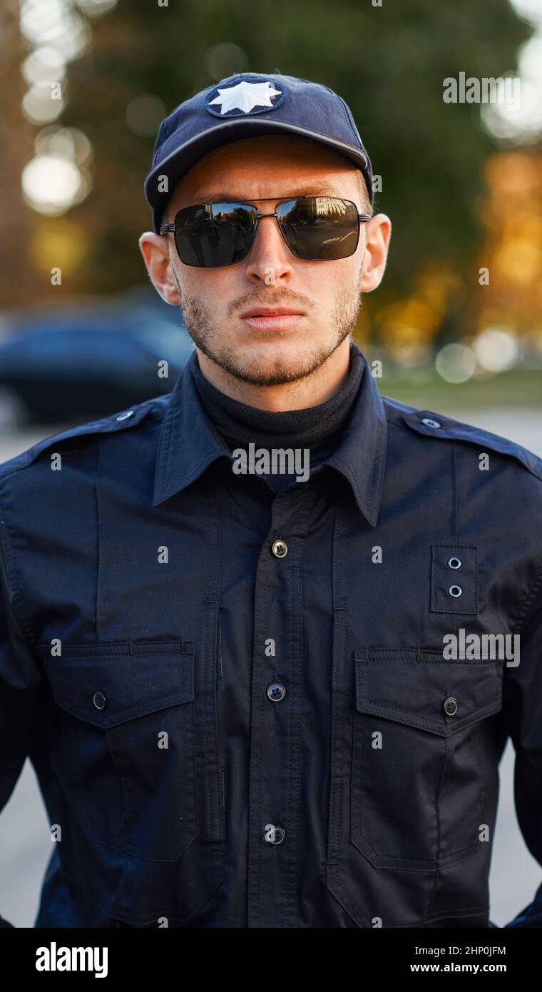 A police officer poses in uniform and sunglasses. Policeman protect the ...