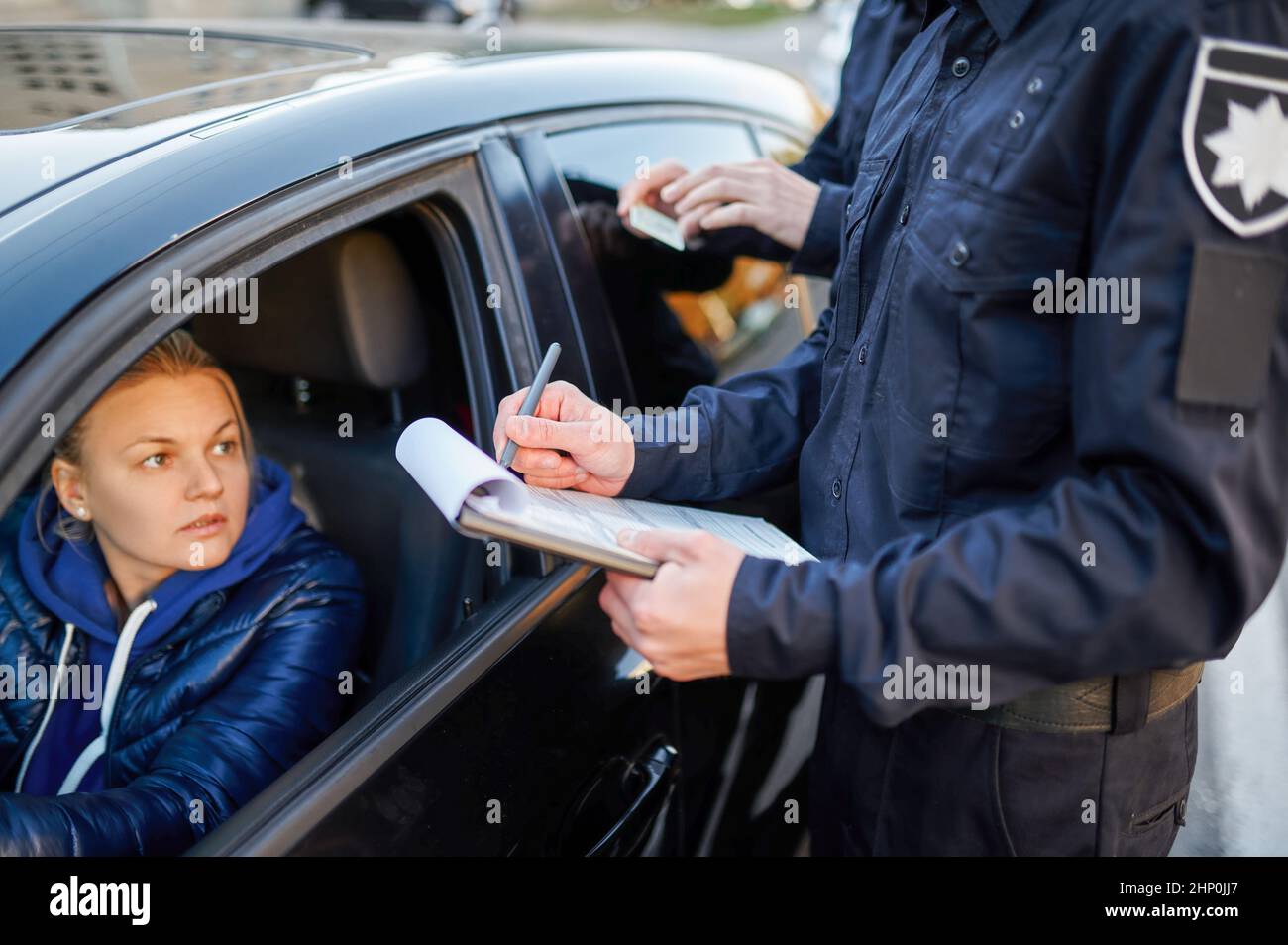 Police patrol checking driver's license of female driver. Policemen in