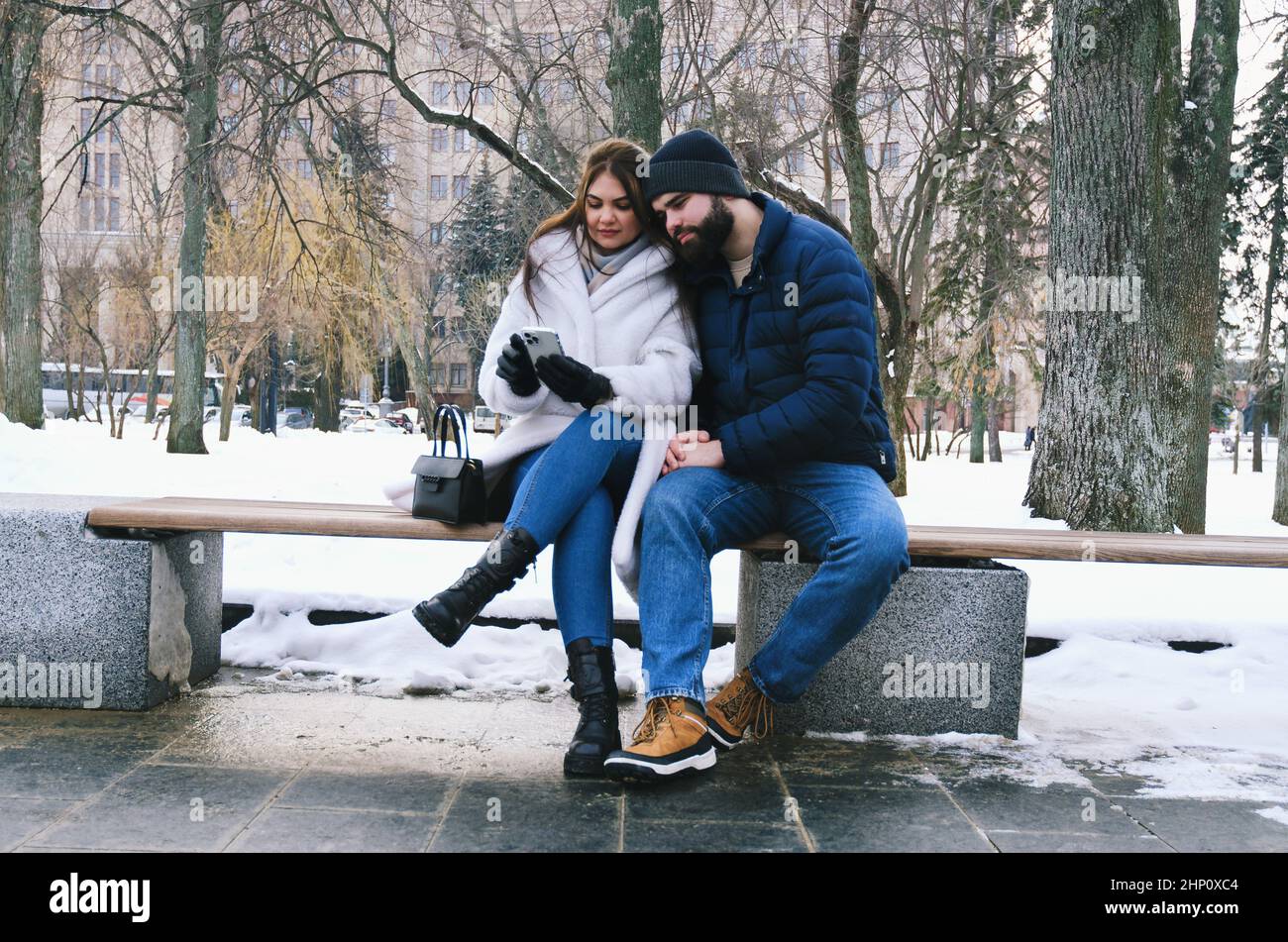 couple walking in city. Young business man in a blue jacket with a beard. And a cute woman in long coat. Family holiday and togetherness, date Stock Photo