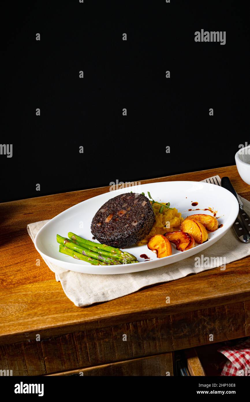 Black pudding with green asparagus and fried apple Stock Photo