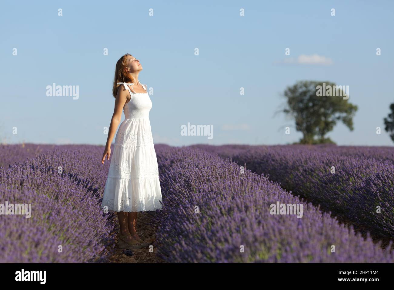 Full body portrait of woman in white dress breathing fresh air in ...