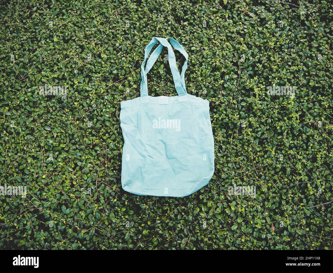 Blank blue Mockup Linen Cotton Tote Bag on Green Bush Trees Foliage