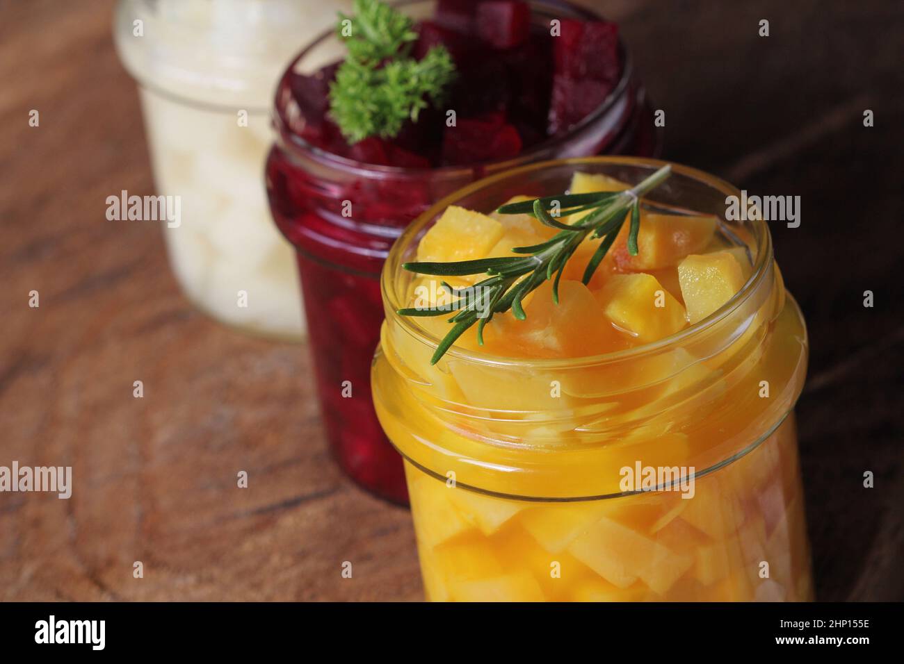 Pickled red, white, orange beet in glass jars. Variety pickles on rustic background Stock Photo