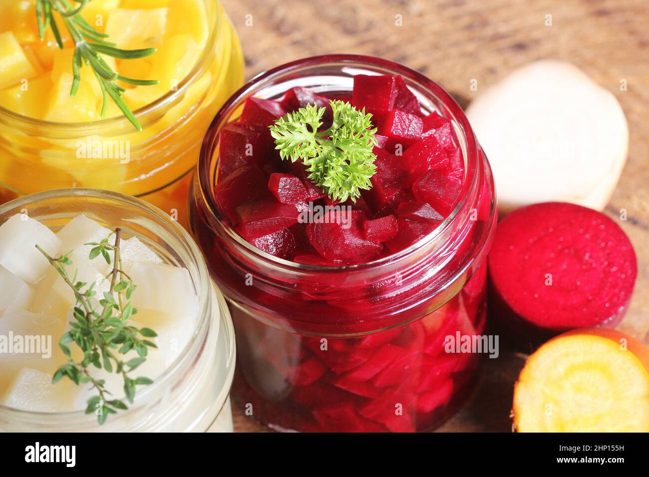 Pickled red, white, orange beet in glass jars. Variety pickles on rustic background Stock Photo