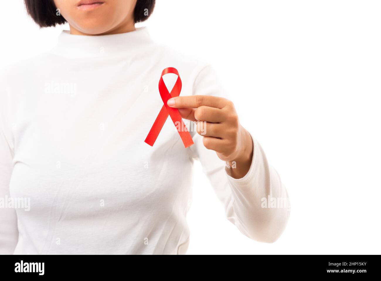 Woman holding HIV AIDS awareness red ribbon in studio shot isolated on ...