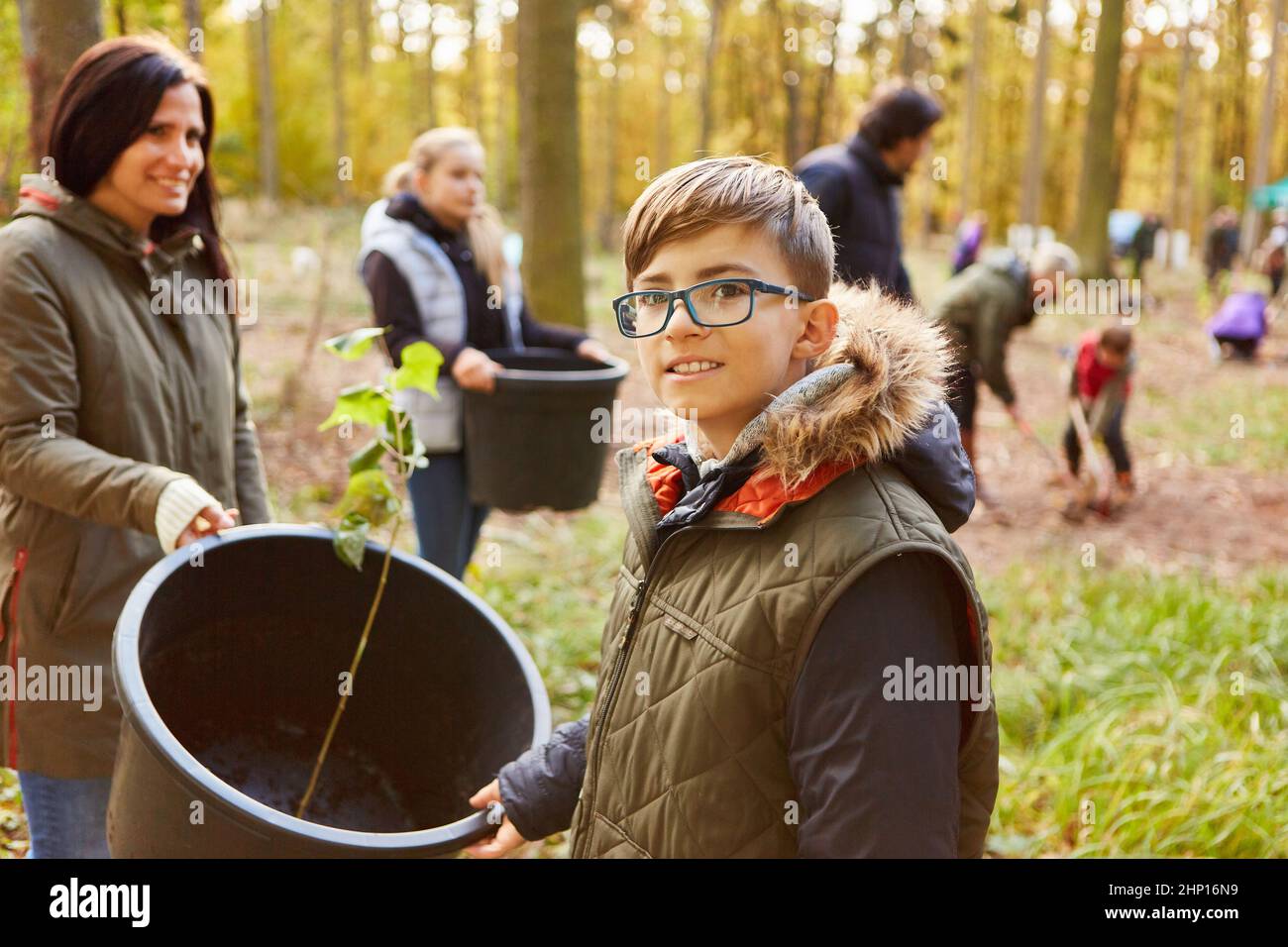 Little boy helps family plant a tree in the forest for sustainable reforestation Stock Photo