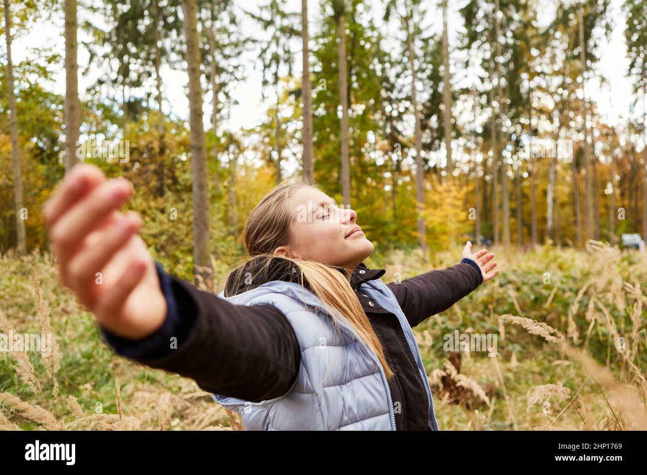 Girl with arms outstretched in the forest doing a yoga breathing exercise for relaxation Stock Photo